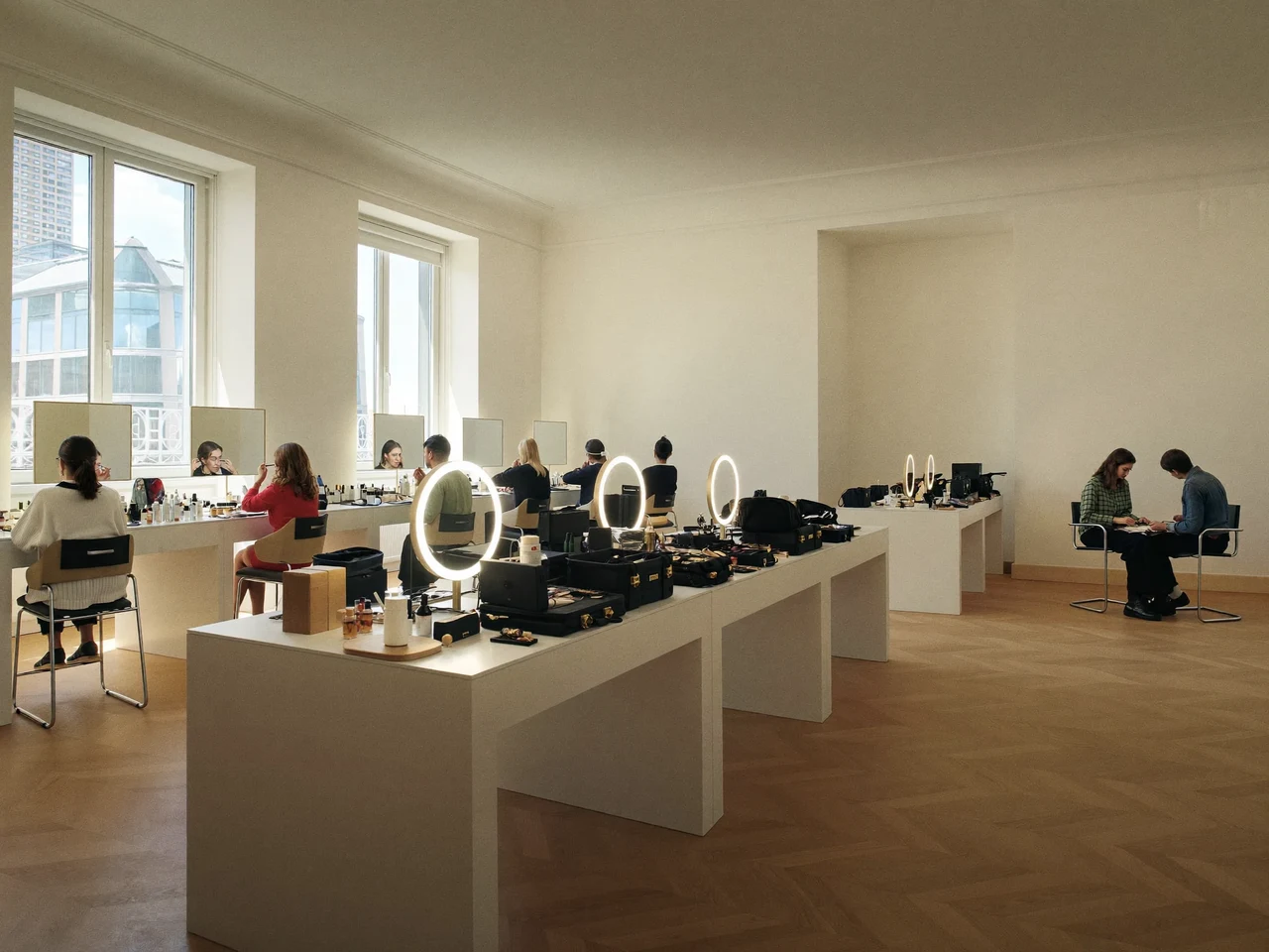 Atelier lumineux avec postes de maquillage, miroirs éclairés et participants face à leurs modèles