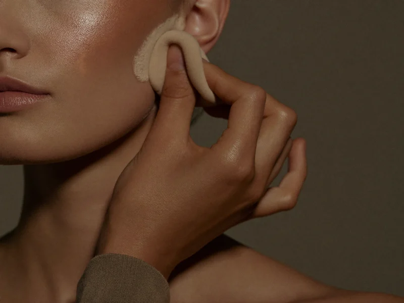 Démonstration de fondu du fond de teint à l'éponge sur la joue d'un modèle