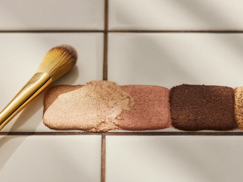 Détail macro de pigments en poudre et d'un pinceau fin sur une surface blanche